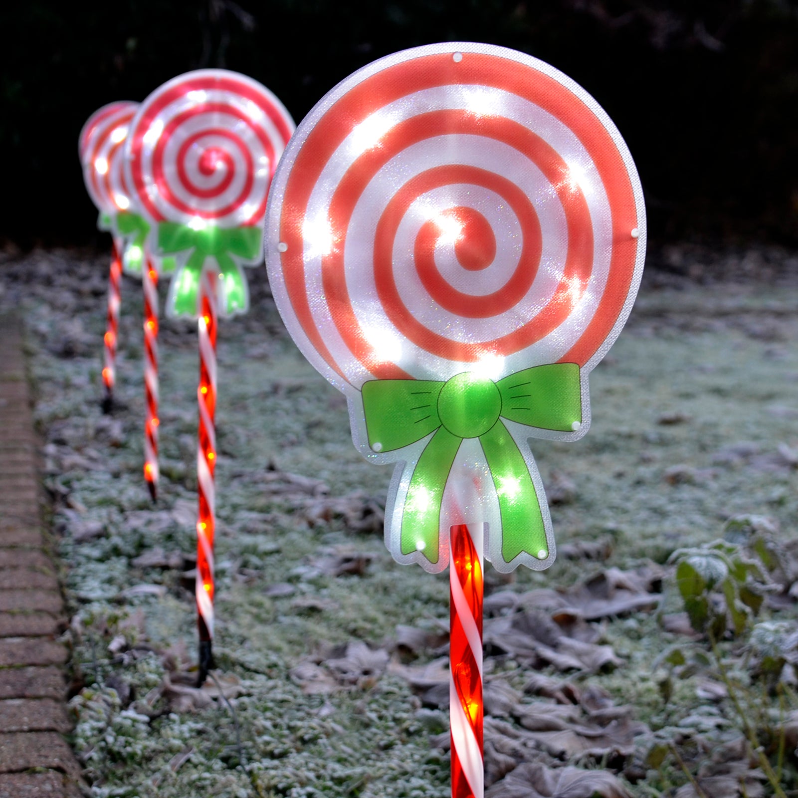 Christmas candy cane lollipop pathway lights lit up in a frosty garden